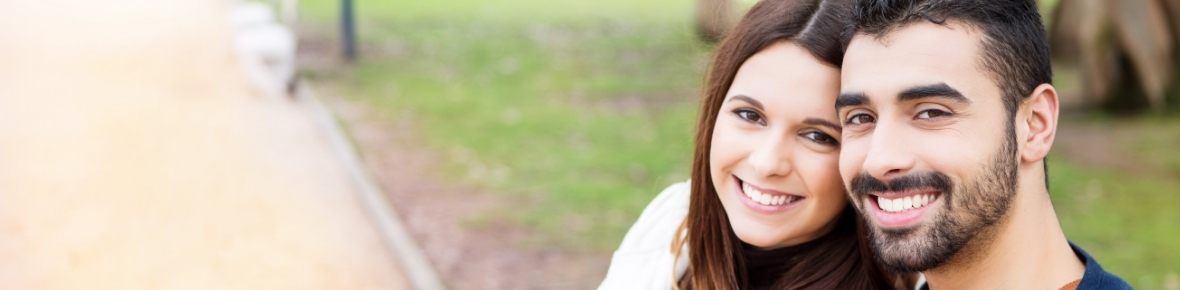 Young couple smiling outdoors after visiting dental office in Cherry Hill