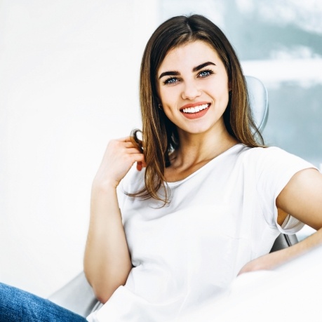 Woman in white tee shirt smiling in dental chair