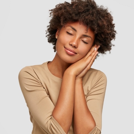 Woman making pillow shape with her hands and pretending to sleep