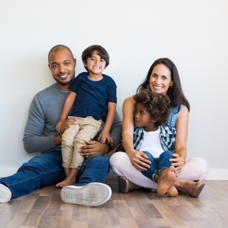 Smiling family of four sitting on wood floor