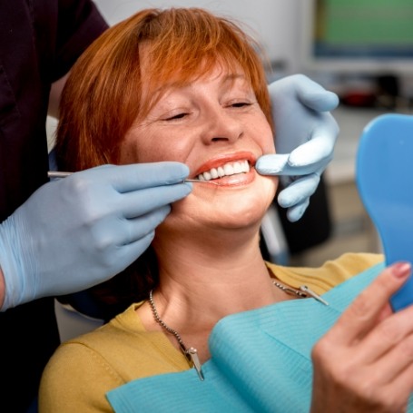 Dental patient looking at her new smile in a mirror