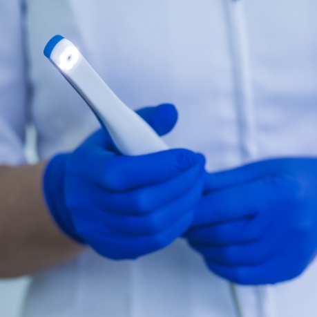 Dental professional holding a thin white intraoral camera