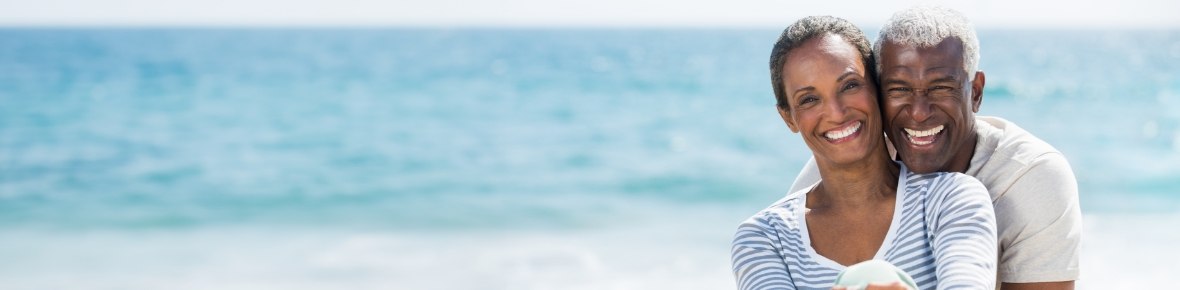 Senior couple smiling and hugging on the beach