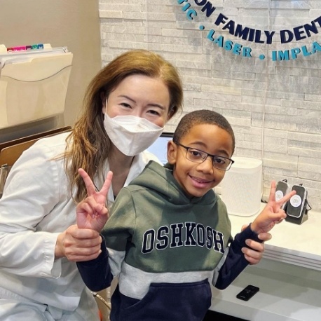 Doctor Lee smiling with young male dental patient giving peace signs