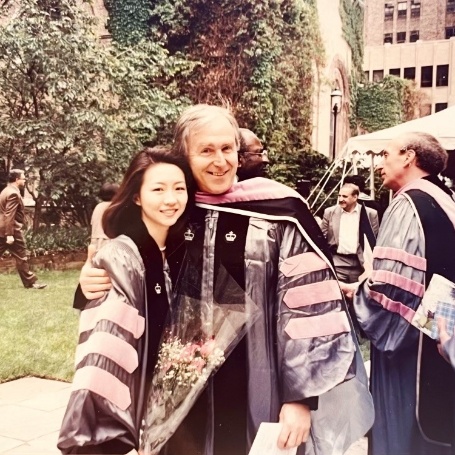 Doctor Lee in graduation robes smiling with an older man also in graduation robes