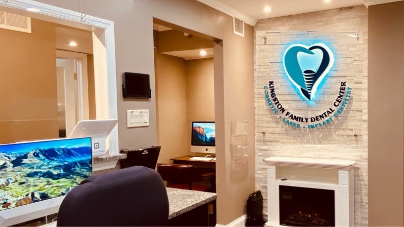 Desk with computer and sign on wall for Kingston Family Cosmetic Dental Center