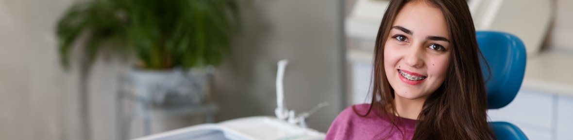 Teenage girl in dental chair with braces smiling