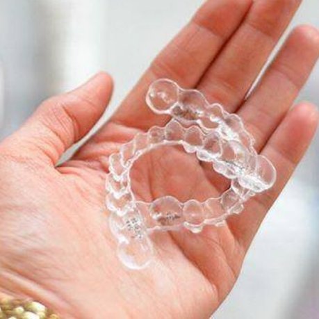 Hand holding two Invisalign clear aligners
