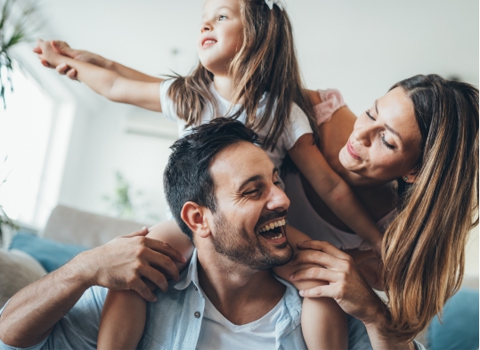 Family of three laughing together on couch