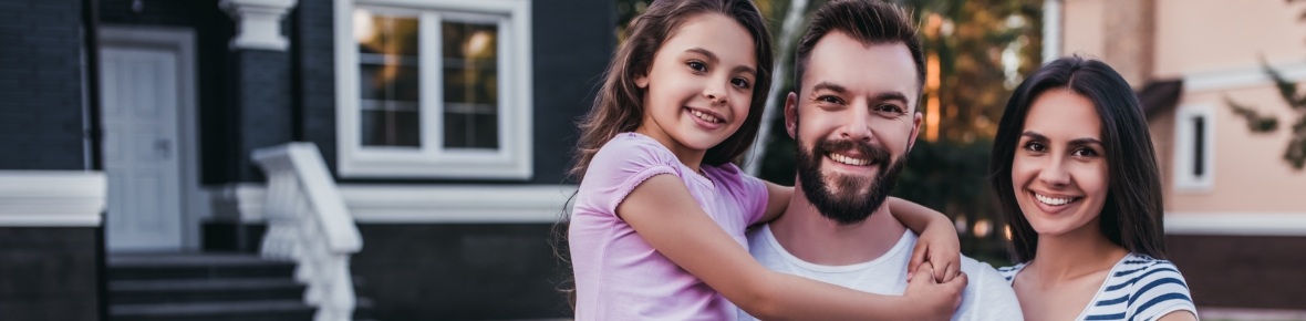 Family of three smiling in their front yard