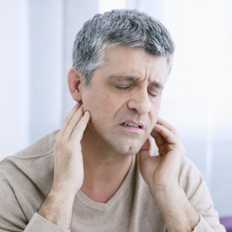 Man holding both sides of his jaw in pain